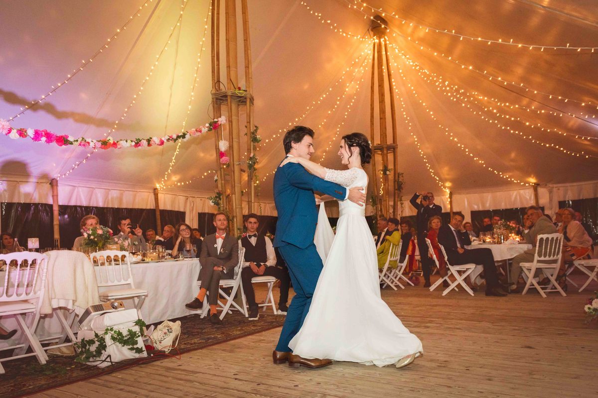 Dîner de mariage en extérieur sous les guirlandes lumineuses, tour d'un château au crépuscule