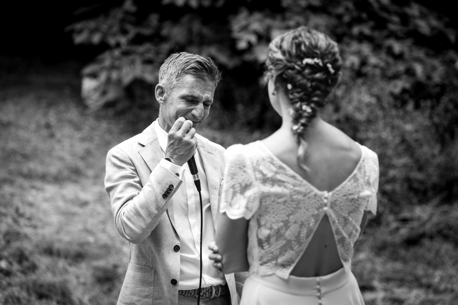 Le marié essuie une larme pendant la cérémonie, la mariée de dos en robe de dentelle au dos ouvert