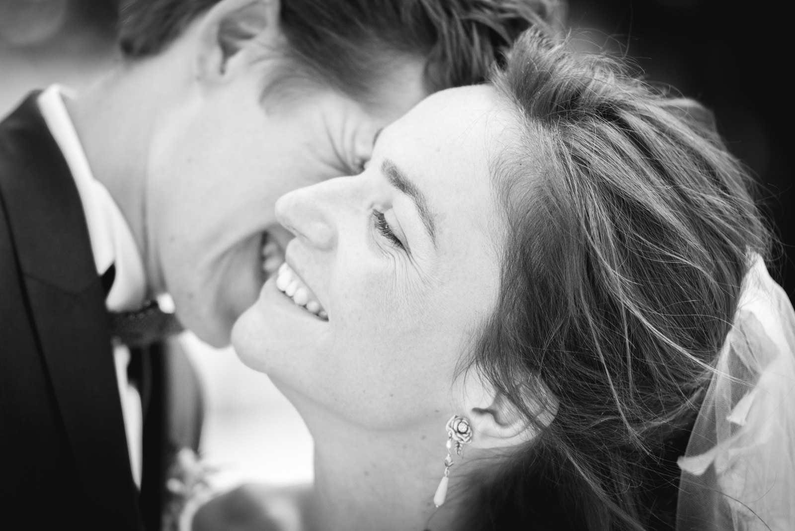 Gros plan sur le rire de la mariée pendant que le marié l'embrasse sur la joue
