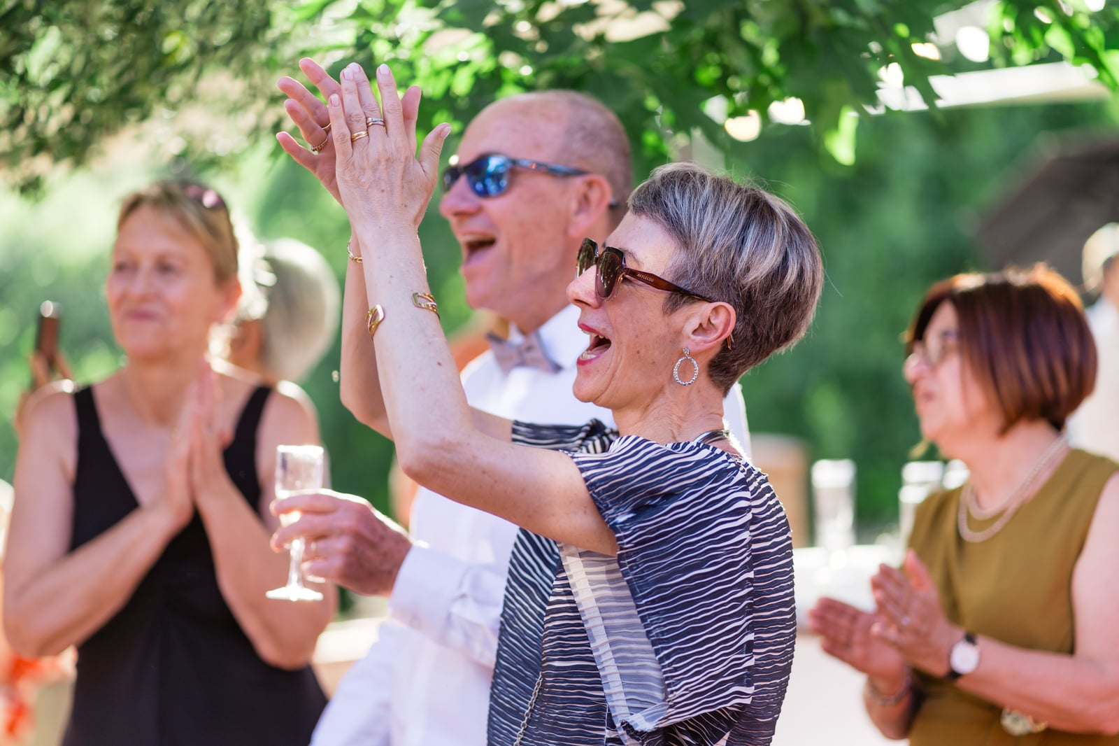 Des invités applaudissent, coupes de champagne à la main, pendant les discours