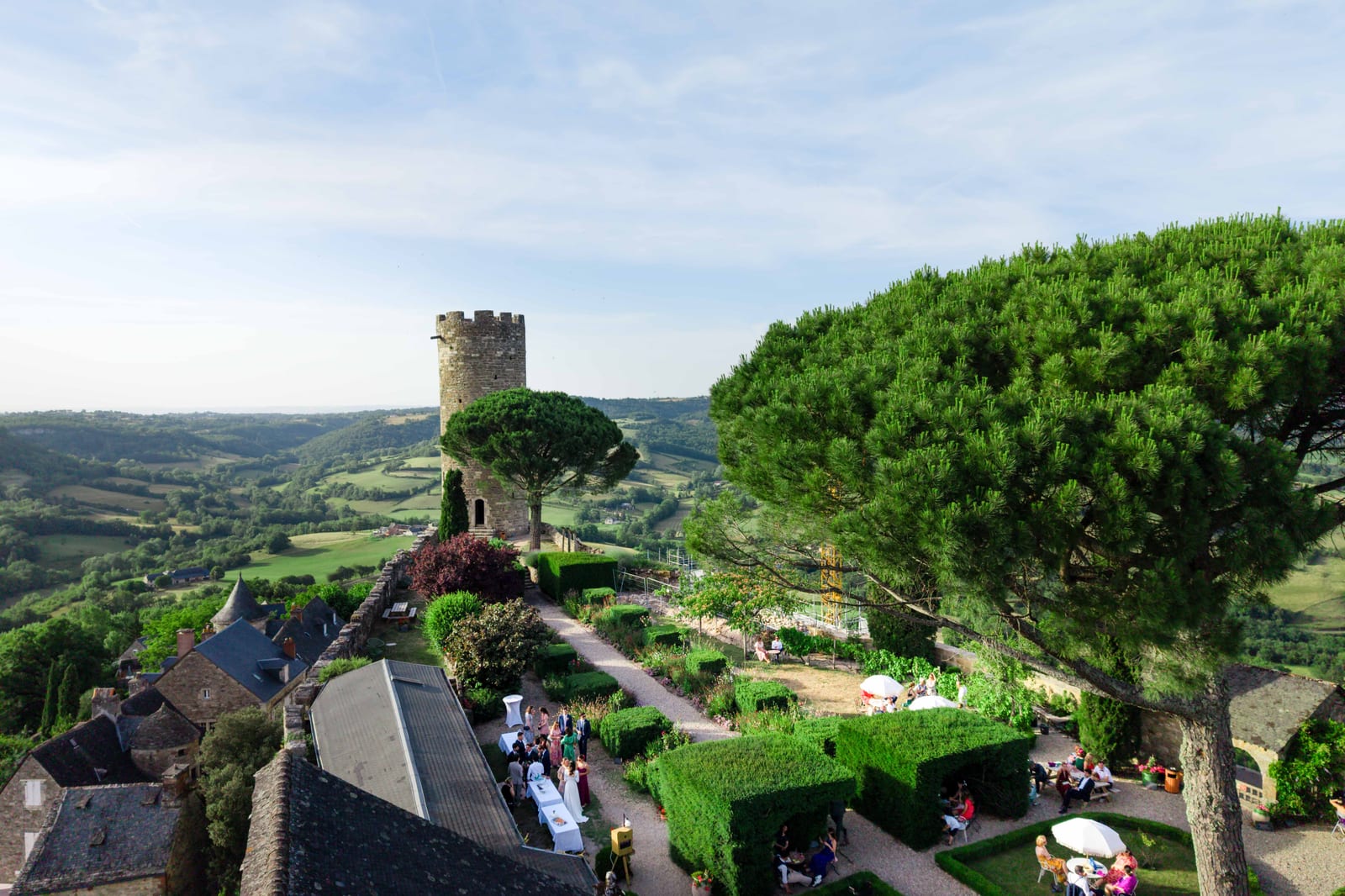 Vue plongeante sur un village perché et sa tour médiévale, la réception installée dans les jardins en contrebas