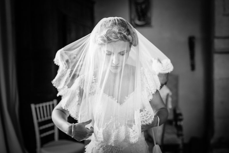 Mariée sous son voile de dentelle pendant les préparatifs, noir et blanc, château de Sauvebœuf en Dordogne